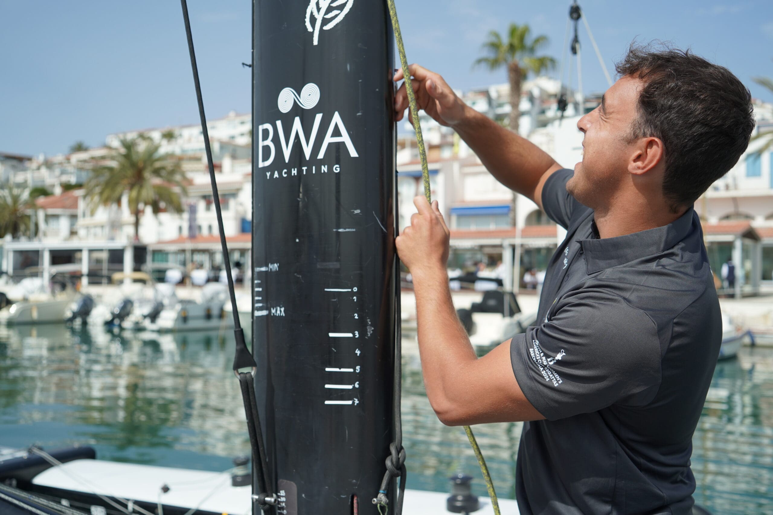 Man pulling a rope on a luxury super yacht in the harbour with the BWA Yachting logo on the boat.