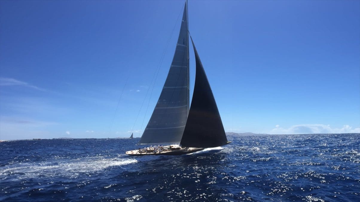 Luxury sailing superyacht leaning towards the camera on blue slightly choppy seas with clear blue skys.