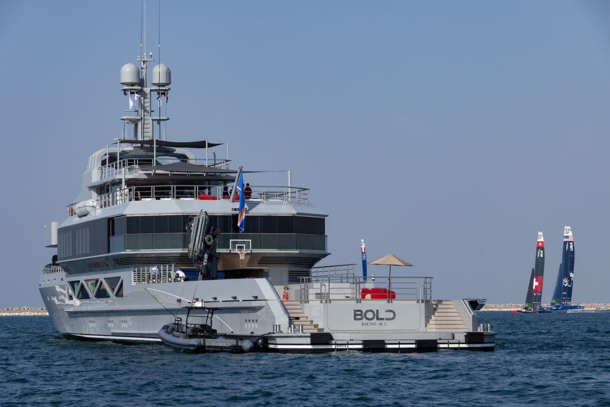 Superyacth on water with two racing yachts in the distance